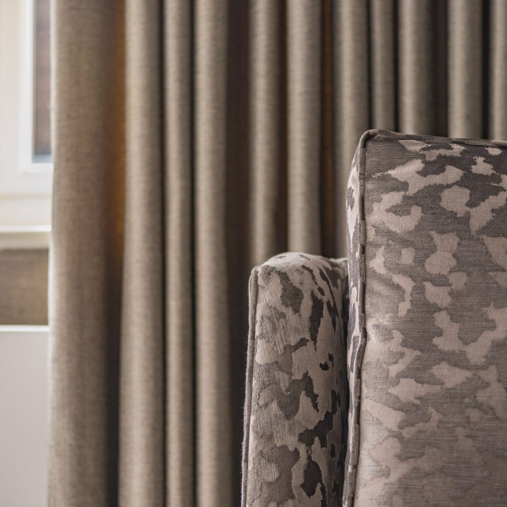 patterned chair in front of beige curtain